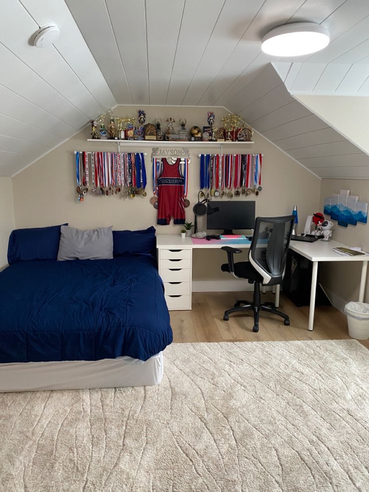 an attic bedroom with a bed, desk and computer on top of the dressers