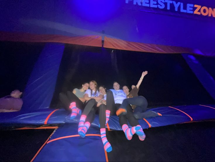 three people sitting on top of a trampoline in the air with their arms up