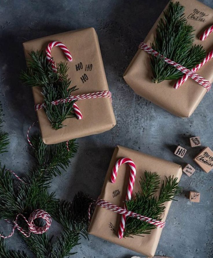 three wrapped presents tied with twine and candy canes on top of a table