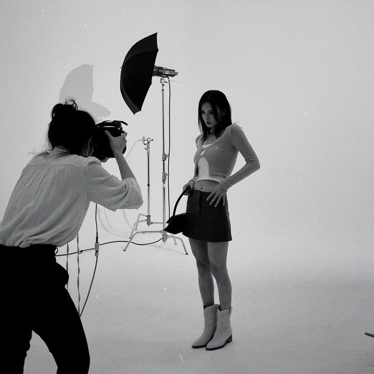 a black and white photo of a woman in front of a camera with an umbrella