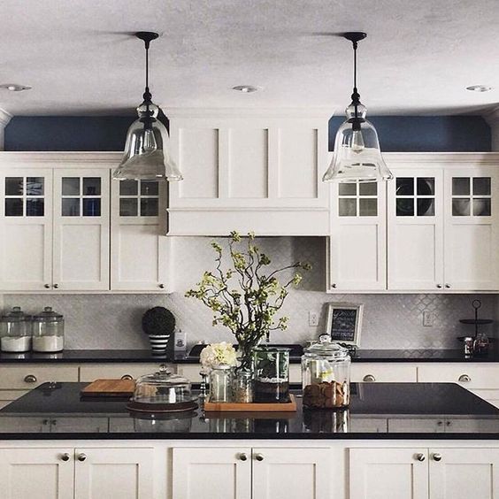 a large kitchen with white cabinets and black counter tops, two pendant lights over the island