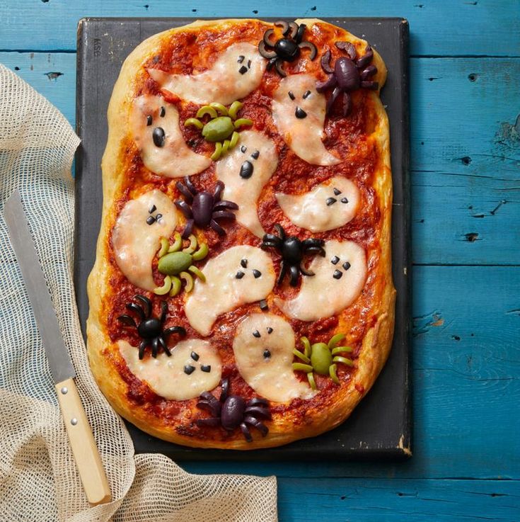 a pizza topped with lots of toppings sitting on top of a pan next to a knife