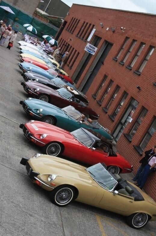 a row of cars parked next to each other on the side of a road in front of a brick building