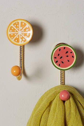 two pieces of fruit hanging from hooks on a wall next to a towel and ball