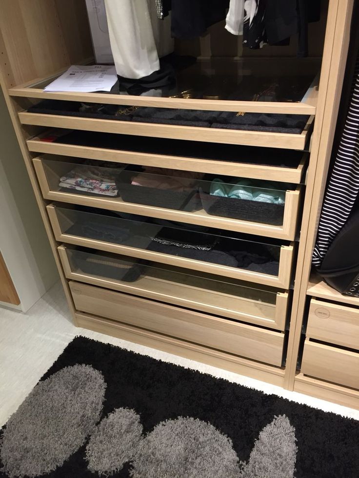 a closet with several drawers and clothes hanging on the wall next to an area rug