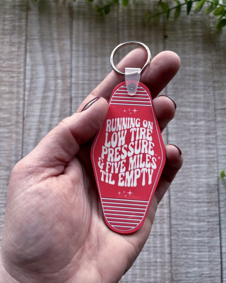 a hand holding a red keychain that says running on low tire pressure five miles per mile