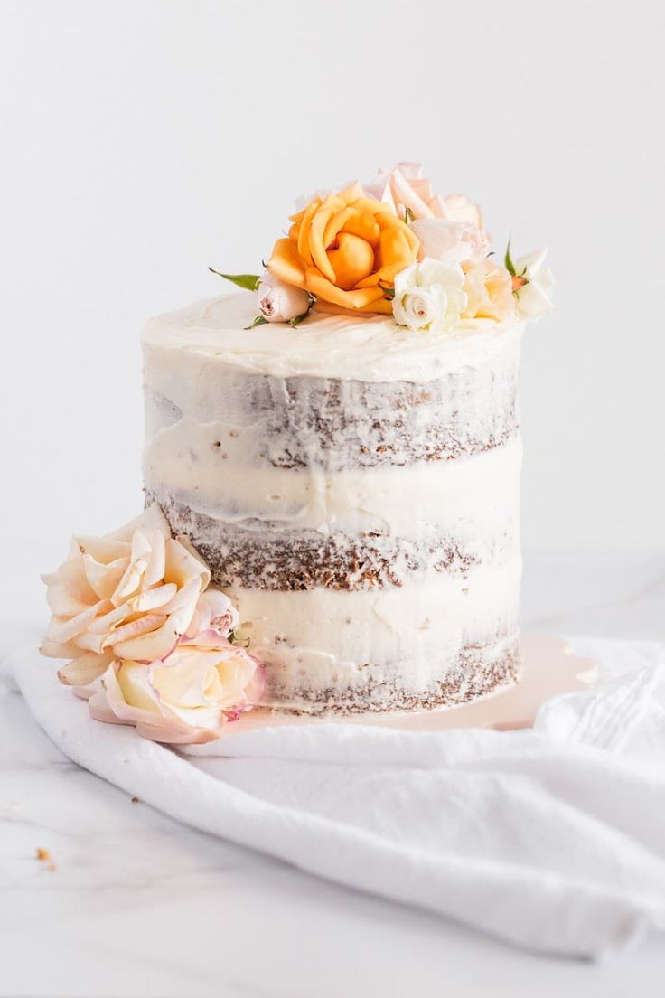 a three layer cake with white frosting and flowers on top