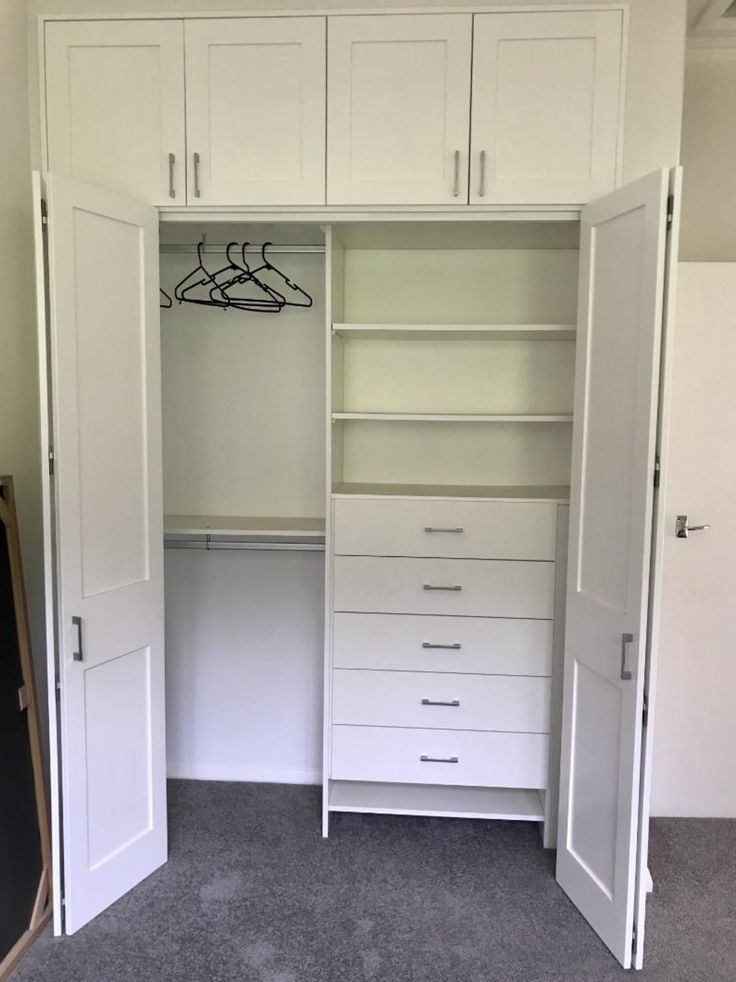 an empty closet with white cabinets and drawers