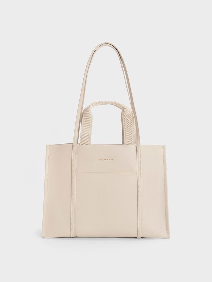 If you have an affinity for neutrals, the Shalia bag is a must-have addition to your collection. With its double top handles and versatile strap, this gem offers multiple styling options. The soft beige shade adds an aesthetically pleasing touch, making you look chic and polished from every angle while effortlessly complementing any ensemble you choose. For a simple yet elegant look, pair it with a pencil skirt and printed blouse combination. Tote Bag For Work, Edgy Bags, Adjustable Bag Strap, Buy Bags, Adjustable Bag, Size Chart For Kids, Soft Beige, Charts For Kids, Charles Keith