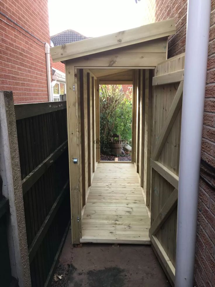 an open wooden door leading into a garden area with brick buildings in the back ground