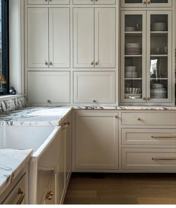 a kitchen with white cabinets and marble counter tops