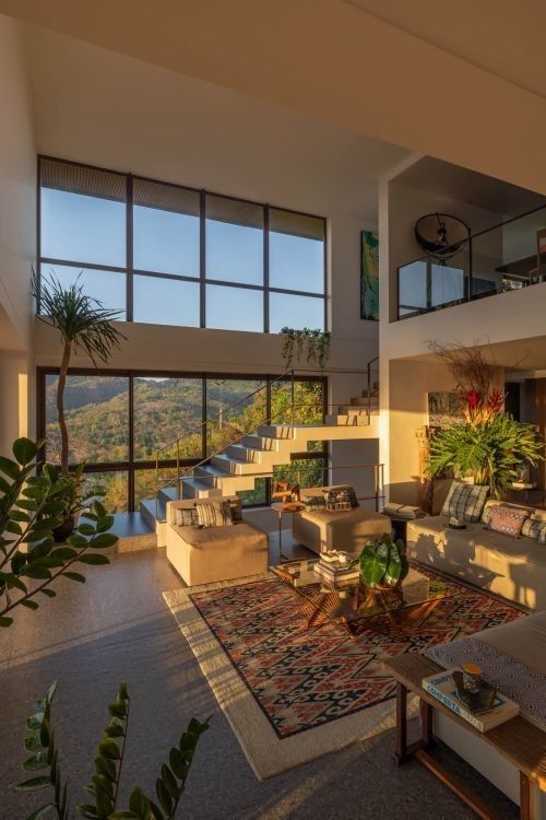 a living room filled with lots of furniture and large windows overlooking the mountains in the distance