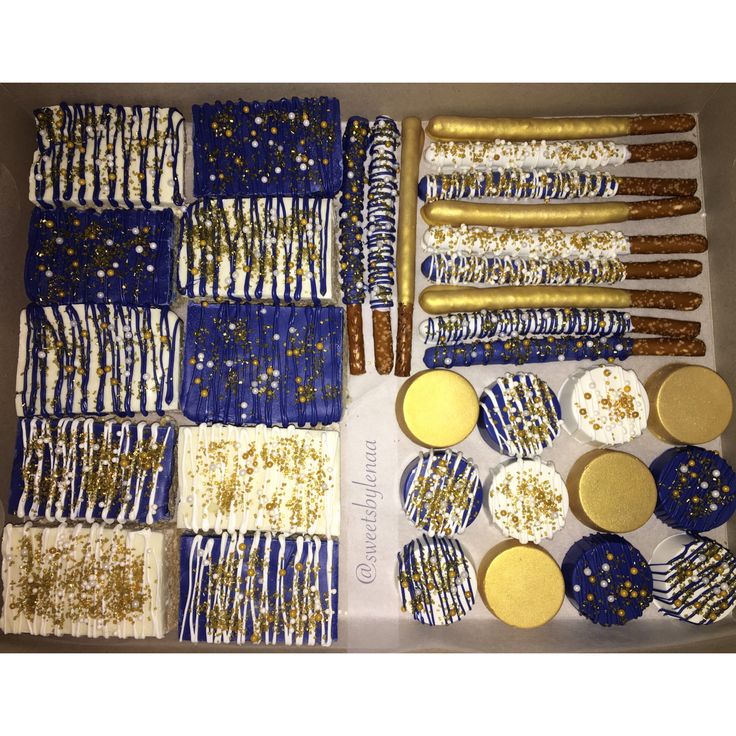 an assortment of cookies and desserts are displayed in a box with gold foil sprinkles