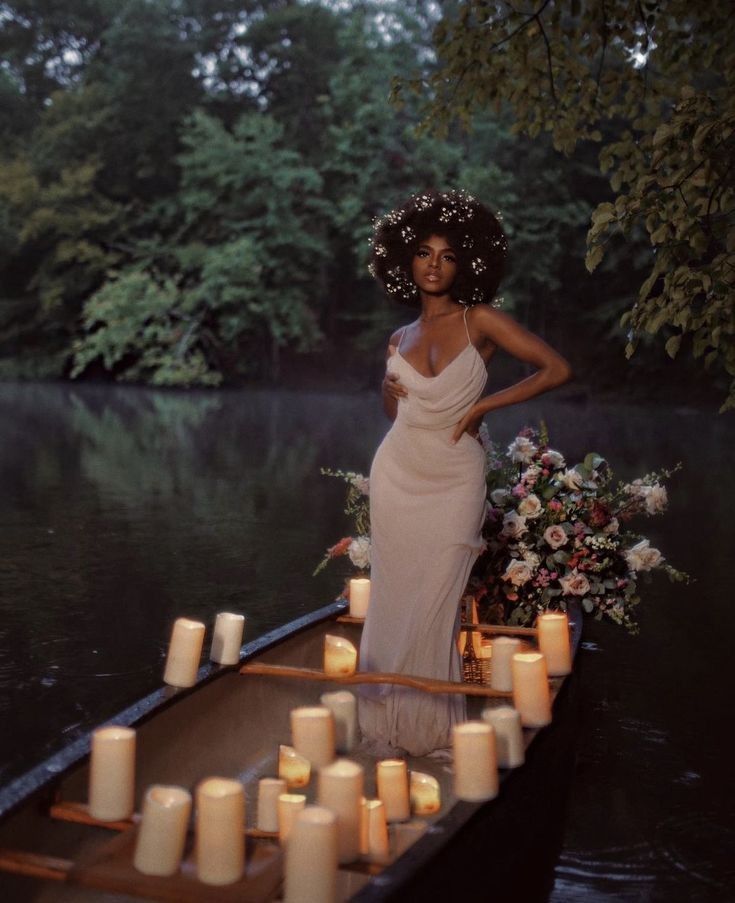 a woman in a white dress is standing on a boat with candles floating around her