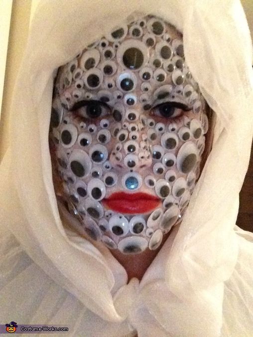 a woman with her face covered in white cloths and silver circles on her face