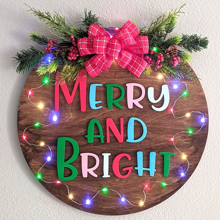 a merry and bright wooden sign hanging on the side of a wall with christmas lights