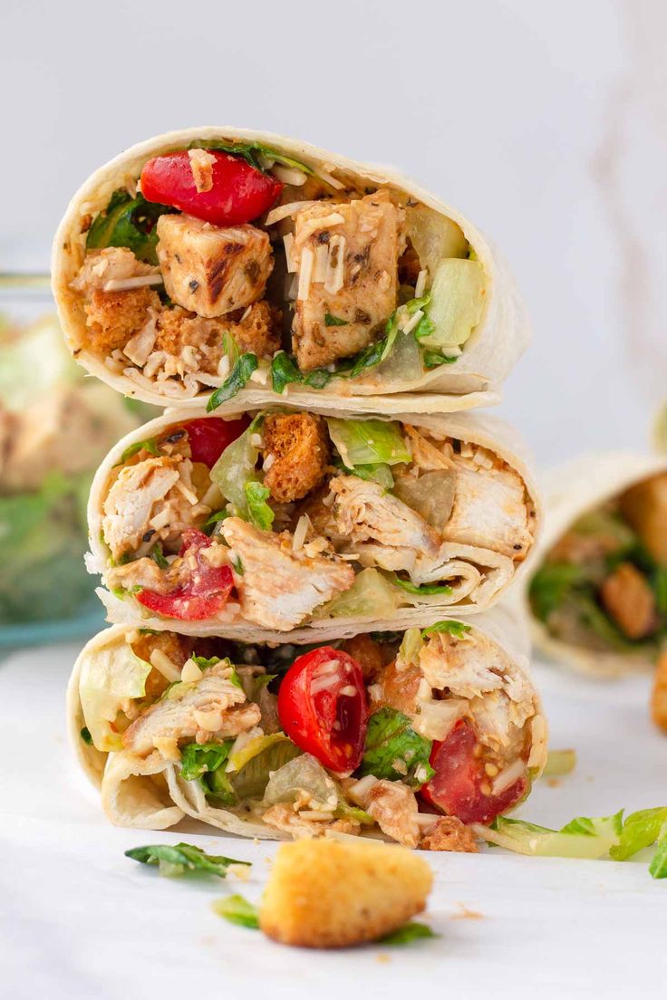 three wraps stacked on top of each other with chicken, lettuce and tomatoes