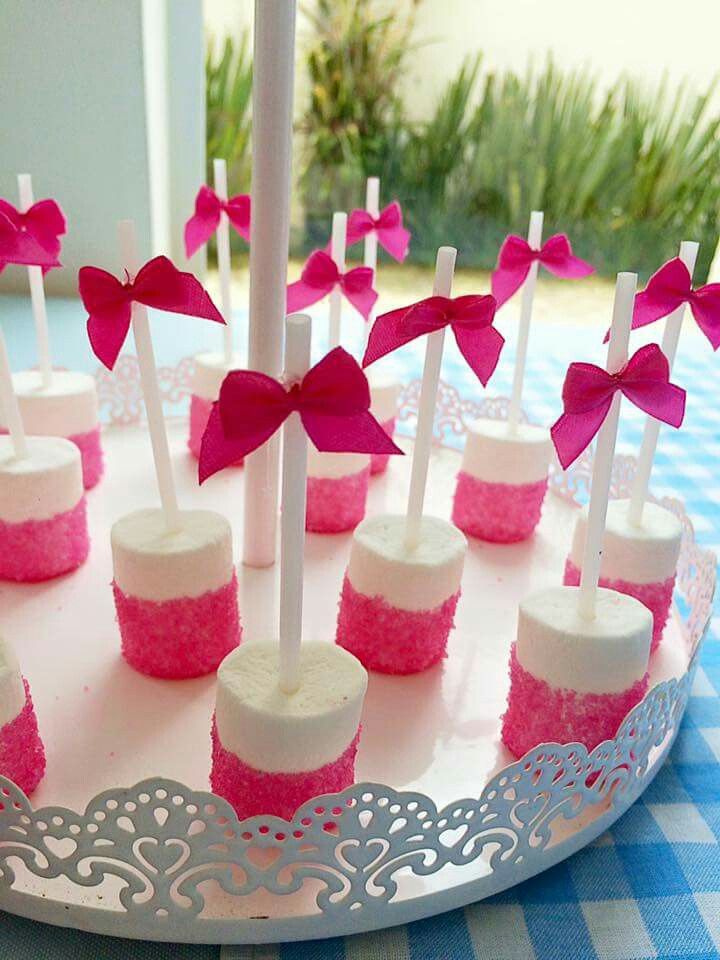 cake pops with pink and white frosting are on a platter decorated with bows