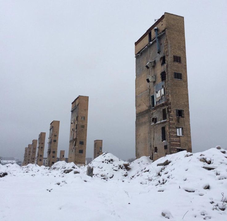 an abandoned building in the middle of winter with snow on the ground and windows missing