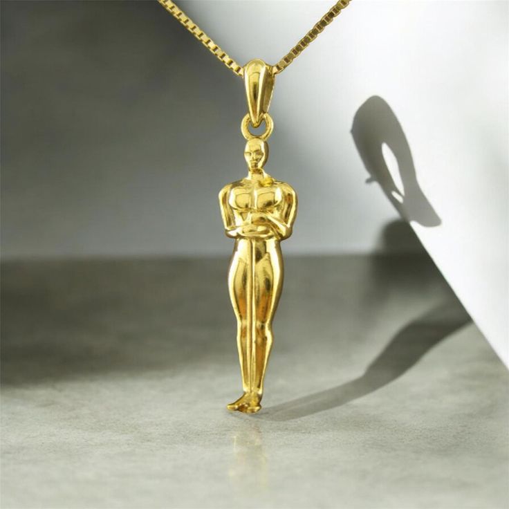 This handcrafted 14K gold Oscar pendant is a perfect example of elegance and style. Weighing approximately 3.55 grams, the pendant is paired with a refined 14K gold chain that weighs 1.95 grams. Its unique design and high-quality craftsmanship make it ideal for both special occasions and everyday wear. The pendant comes in a luxurious gift box, making it a perfect choice for gifting a loved one or treating yourself. Luxury Necklaces For Anniversary With Shiny Finish, Luxury Necklaces With Shiny Finish For Anniversary, Formal Sterling Silver Necklace In Gold-tone, Luxury Shiny Finish Necklaces For Anniversary, Classic Yellow Gold Necklace With Shiny Finish, Formal Gold-tone Sterling Silver Necklace, Luxury Gold Necklace Stamped 14k, Classic Gold Necklace As Gift, Fine Jewelry Yellow Gold Necklaces With Shiny Finish