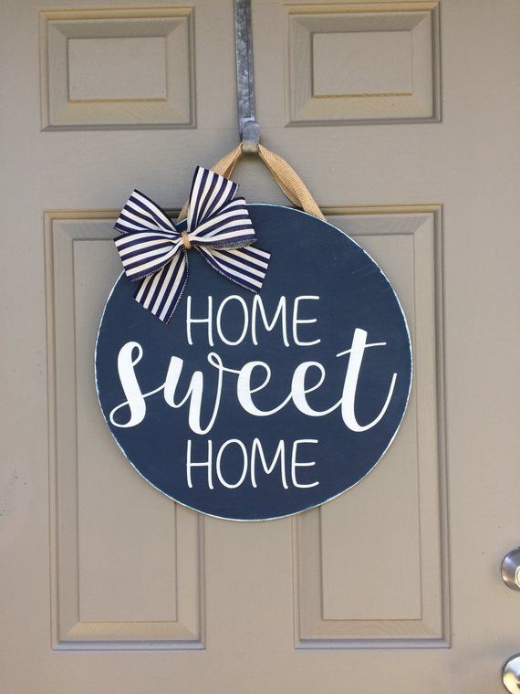 a sign that says home sweet home hanging on the front door with a bow attached to it