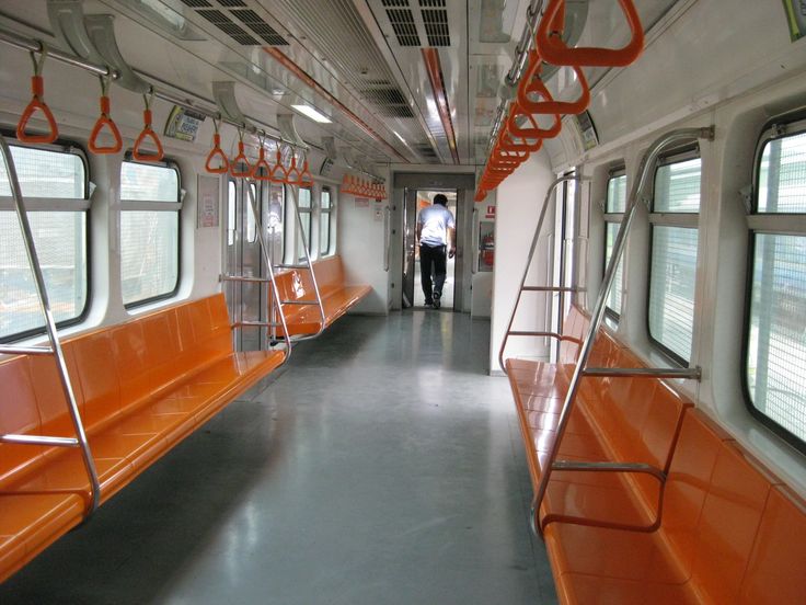 the inside of a subway car with orange seats and railings on both sides,