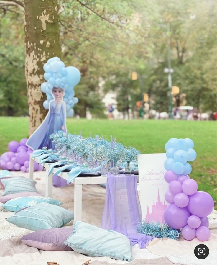 the table is set up with balloons and decorations for an ice princess birthday party,