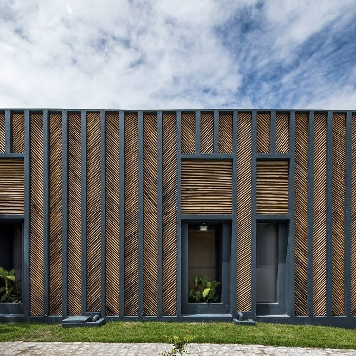 a building with wooden panels on the front and side walls, along with green grass