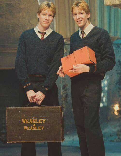 two young men standing next to each other in front of a fire place holding boxes