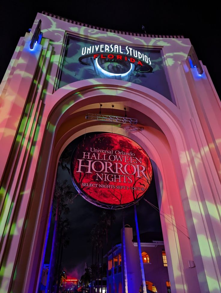 the entrance to universal studios is lit up at night with colorful lights and an animated sign above it