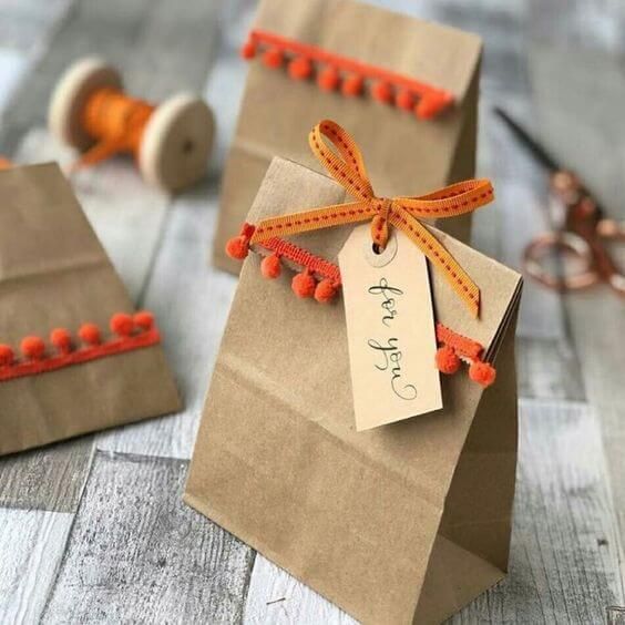 two small brown bags with orange string on them and a tag attached to the handles