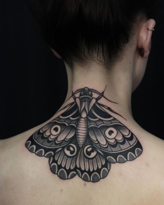 the back of a woman's neck with a black and white butterfly tattoo on it