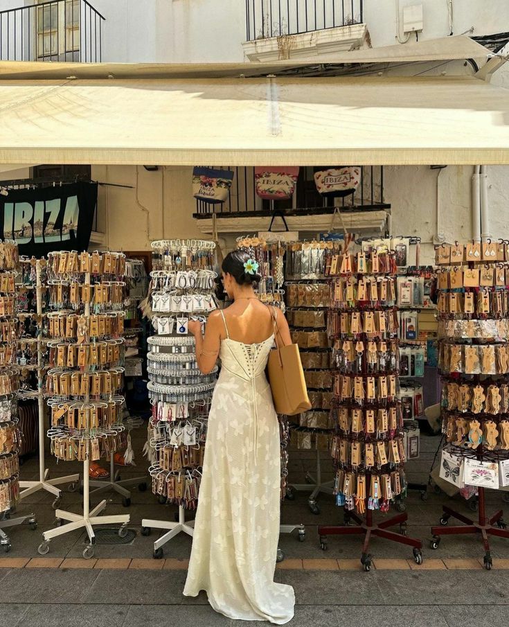 a woman standing in front of a store with lots of items on display behind her