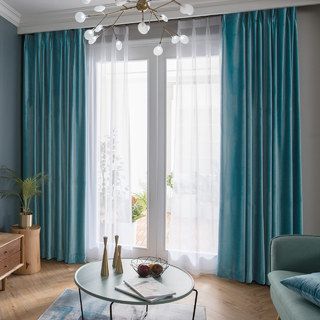 a living room with blue drapes and two vases on top of the coffee table