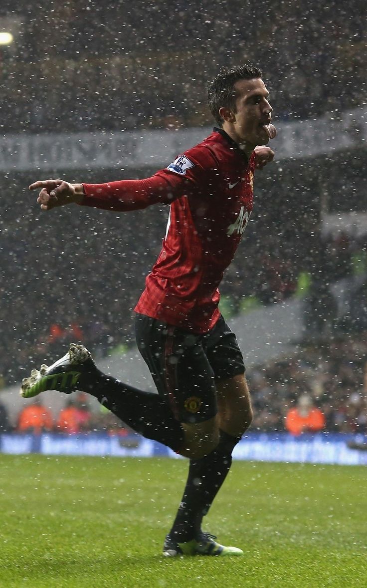 a soccer player is running in the rain with his arms out to catch the ball