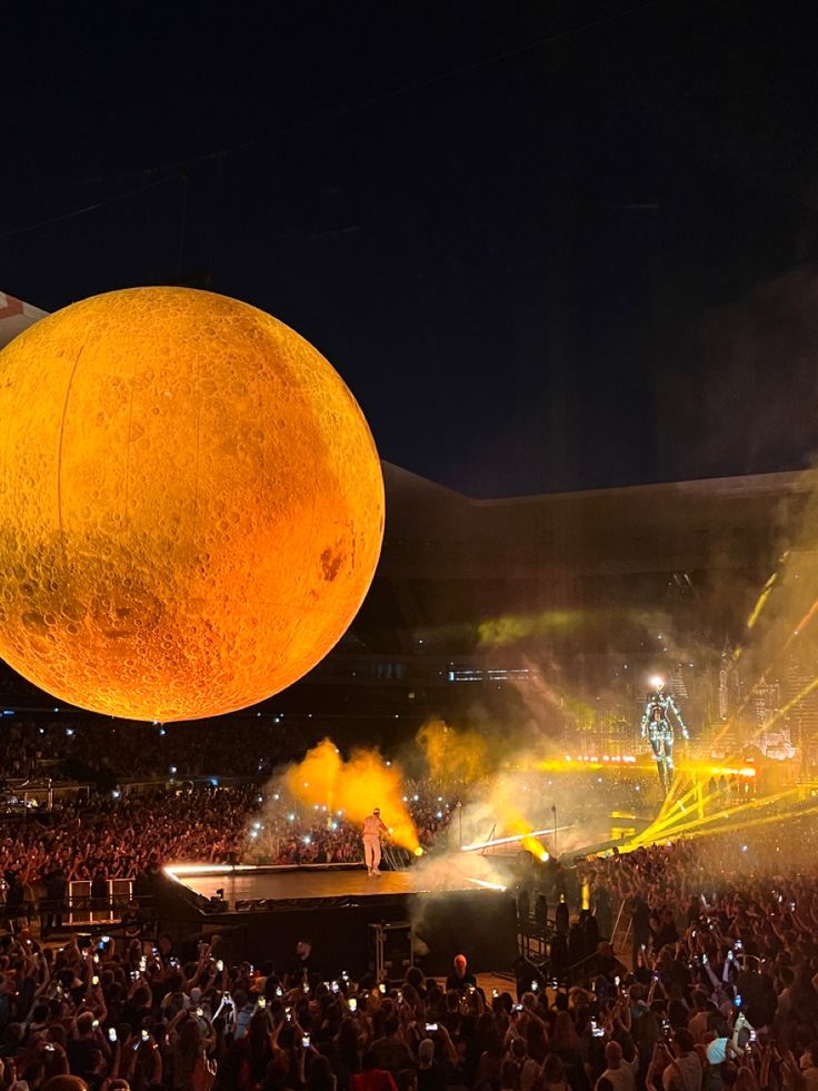 a large orange is suspended from the air at a concert