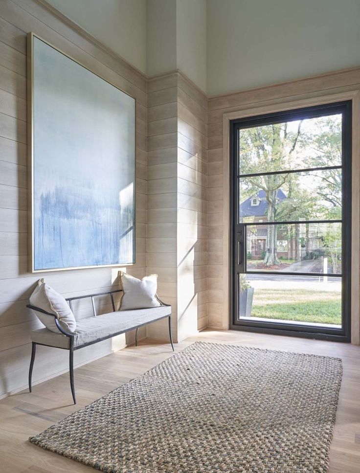 a living room with a large painting on the wall next to a bench and window