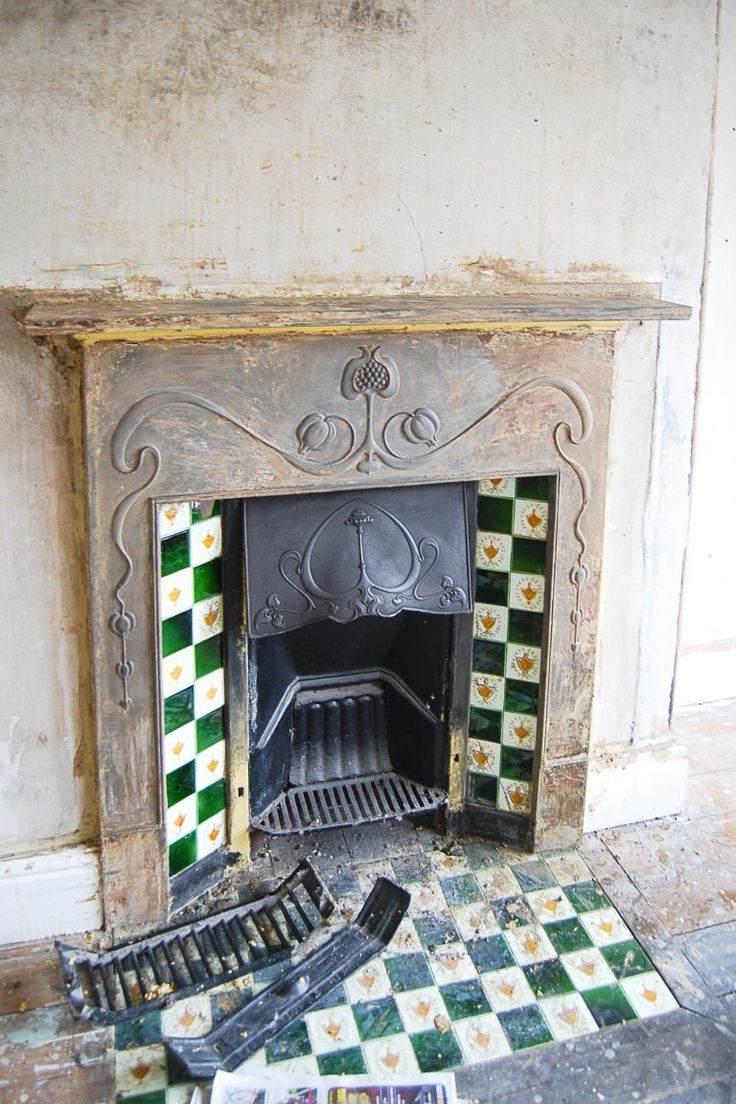 an old fireplace with green and white tiles