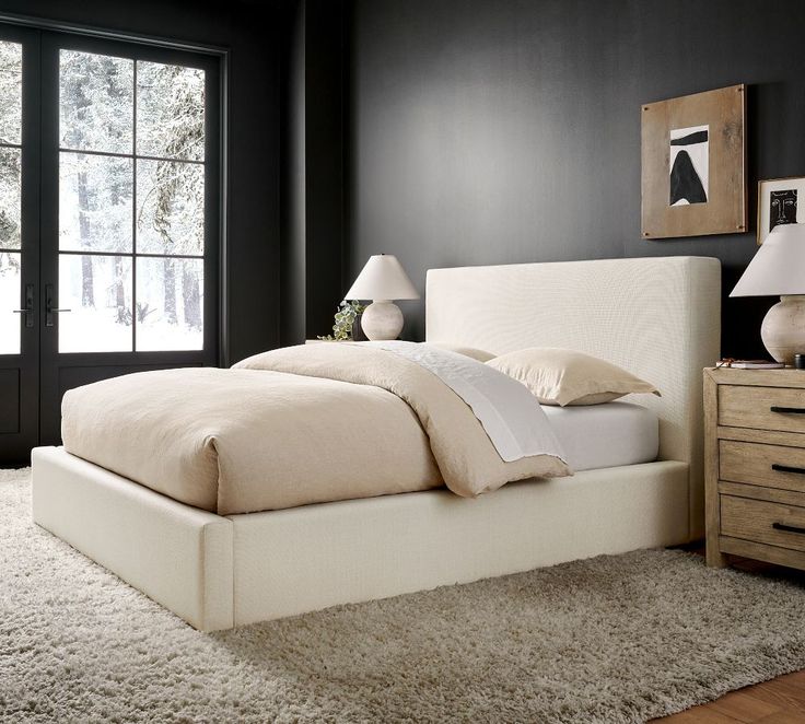 a white bed sitting on top of a wooden floor next to a dresser and window