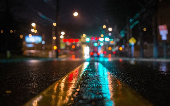 a wet street at night with traffic lights in the background