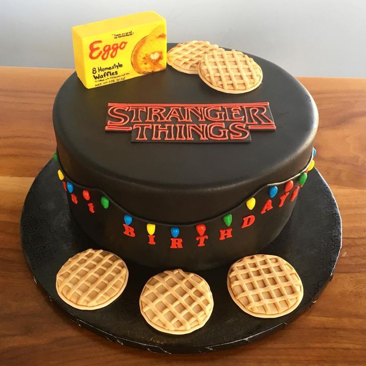 a black cake decorated with waffles and the words strange things on it