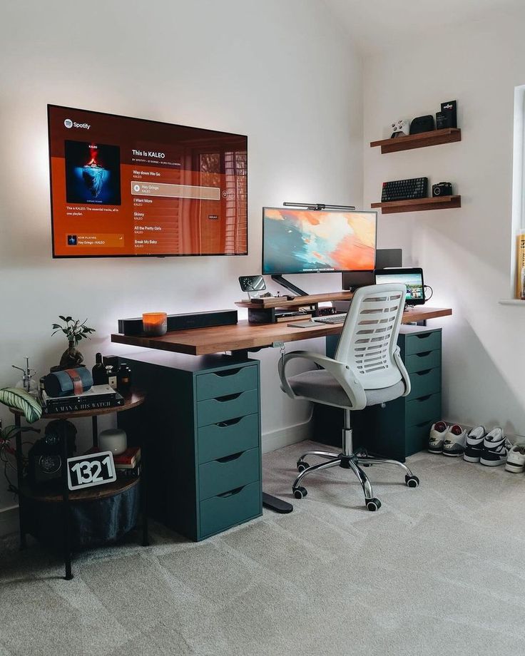 a computer desk with a monitor and keyboard on it in front of a wall mounted television