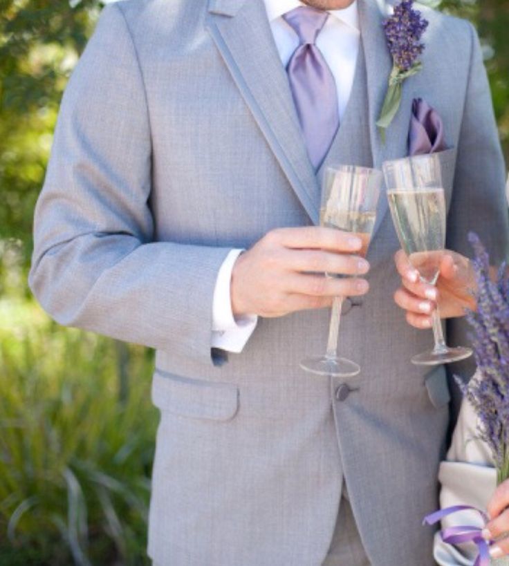 a man in a suit and tie holding a glass of wine next to a woman in a dress