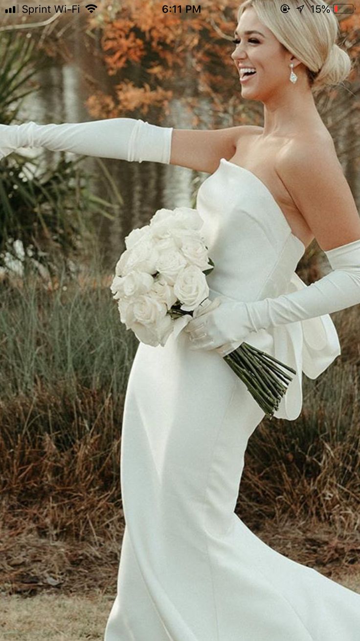 a woman in a white dress and gloves is posing for the camera with her arm outstretched