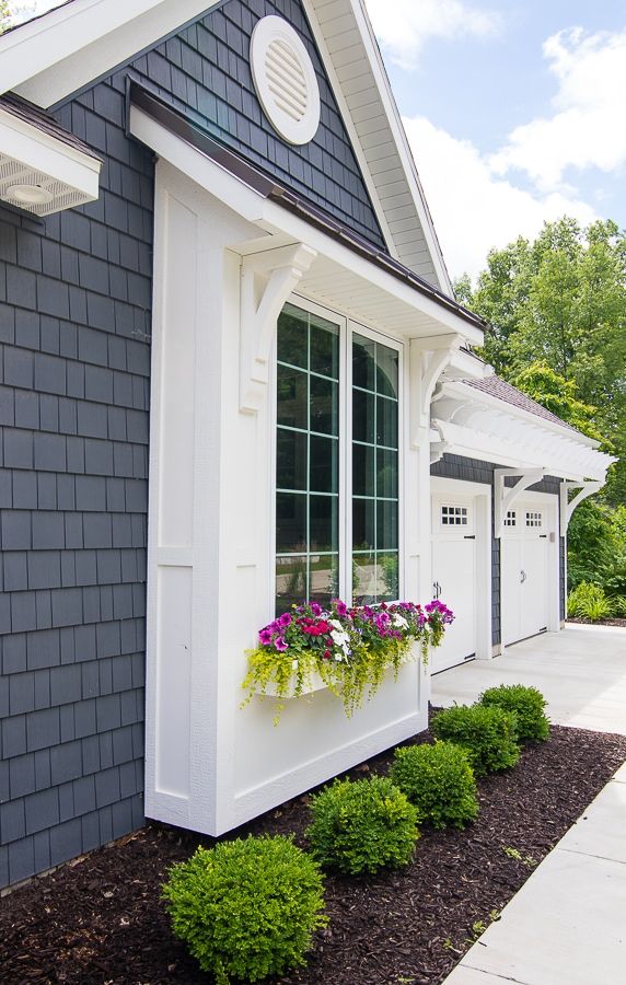 a white and black house with some flowers in the window boxes on the side of it