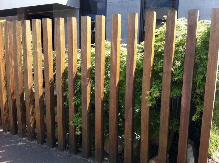 a wooden fence is next to some bushes