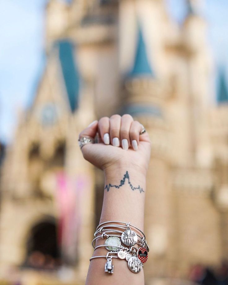 a woman's arm with several bracelets on it and a castle in the background