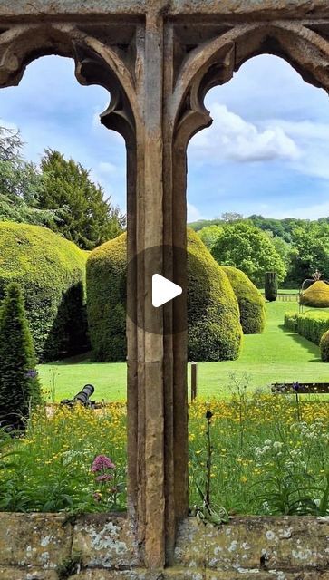 the view from inside an old building looking out onto a lush green garden with trees and bushes