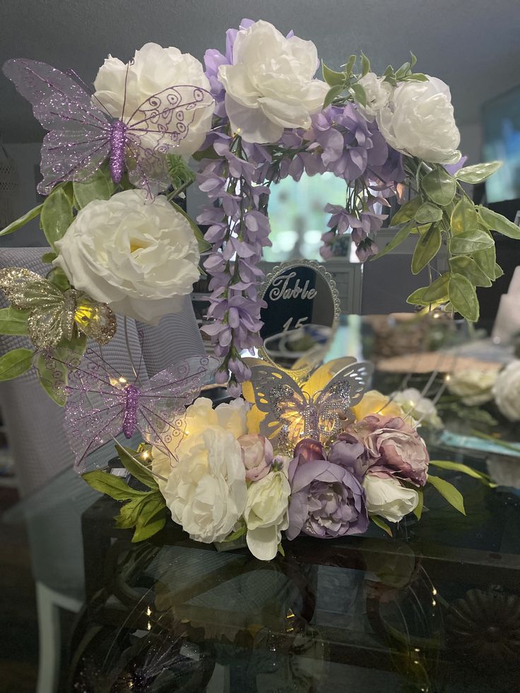 a glass vase with flowers and butterflies in it sitting on a table next to a mirror