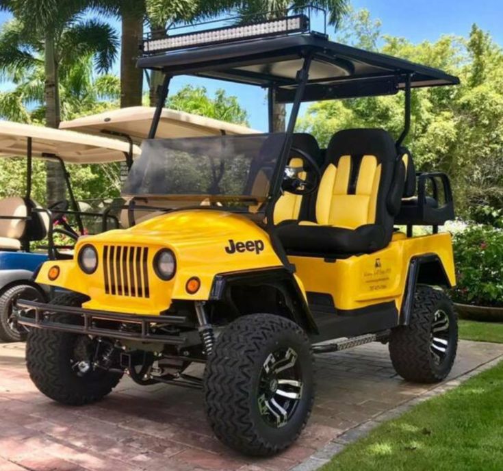 a yellow jeep parked in front of a golf cart